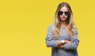 Genç güzel sarışın kadın izole arka plan şüpheci ve sinir, onaylamayan ifade yüz çapraz kolları üzerinde güneş gözlüğü takıyor. Negatif kişi.