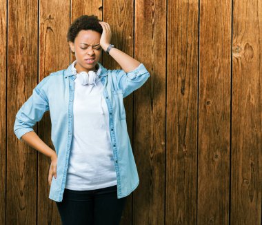 Genç Afrikalı Amerikalı kadın baş ağrısı umutsuz ve stres nedeniyle izole arka plan üzerinde kulaklıklar giyiyor ağrı ve migren. Eller baş.