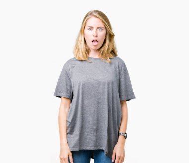 Büyük boy giyen güzel genç kadın şüpheci ve alaycı, rahat t-shirt üzerine şok karşısında izole arka plan açık ağız ile şaşırttı.