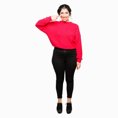 Kırmızı kazak ve topun giyen genç güzel kadın yüz ve burun el parmağı ile işaret, neşeli gülümseyen