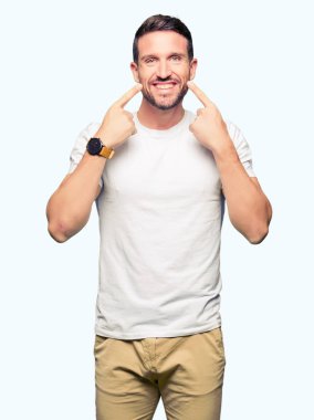 Casual beyaz t-shirt gülen ile giyen yakışıklı adam açık ağız, işaret ve neşeli zorla parmak gülümse