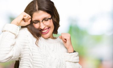 Gülümseyen ve başarı için çığlık çok mutlu ve heyecanlı kaldırdı, silah ile kazanan jest yapıyor gözlüklü genç güzel kadın. Kutlama kavramı.