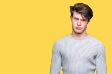 Genç yakışıklı adam sorunu nedeniyle izole arka plan şüpheci ve sinir, papatyanın üzgün üzerinde kış kazak giyiyor. Negatif kişi.