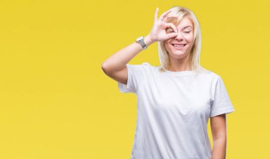 Gülümseyen, parmakları ile mutlu yüz üzerinden seyir göz el ile ok jest yapıyor izole arka plan üzerinde beyaz t-shirt giyen genç güzel sarışın kadın.