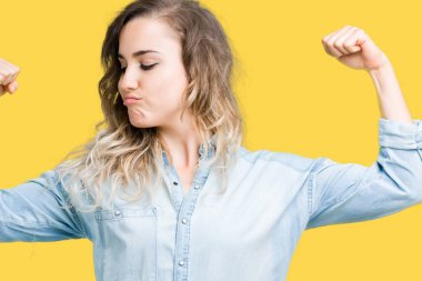 Güzel sarışın genç kadın kol kasları gururlu gülümseyen gösterilen izole arka plan üzerinde. Fitness kavramı.