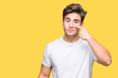 Beyaz t-shirt üzerinde izole giyen genç yakışıklı adam arka plan işaretçi el parmak yüz ve burun, neşeli gülümseyen