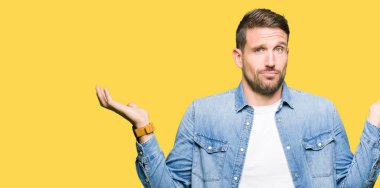 Mavi gözleri ve sakal giyen kot ceket clueless ve kollar ve elleri ile karıştı ifade ile yakışıklı adam kaldırdı. Şüphe kavramı.