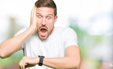 Casual beyaz t-shirt arıyorsunuz seyretmek zaman endişeli, geç korkuyor giyen yakışıklı adam