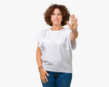 Beyaz giyen güzel orta ager üst düzey kadın t-shirt dur yapıyor izole arka plan üzerine şarkı elin avuç ile. Negatif ve ciddi bir jest yüz ifadesiyle uyarı.