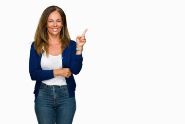 Kameraya bakarak yan el ve parmak ile işaret eden güzel orta yaş rahat yetişkin kadın yüzünde kocaman bir gülümseme ile izole arka plan.