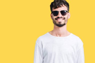 Genç yakışıklı adam yüzünde mutlu ve güzel bir gülümseme ile izole arka plan üzerinde güneş gözlüğü takıyor. Şanslı kişi.
