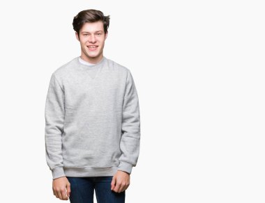Yüz üzerinde mutlu ve serin bir gülümseme ile izole arka plan üzerinde sweatshirt giyen genç yakışıklı sportif adam. Şanslı kişi.