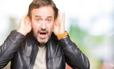 Siyah deri ceket giyen orta yaş yakışıklı adam iki elini de duymaya çalışırken kulak jesti, dedikodu meraklı. İşitme sorunu, sağır