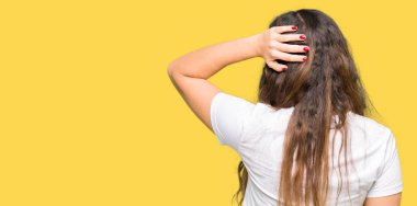 Rahat beyaz t-shirt giyen genç güzel kadın geriye baş el ile şüphe hakkında düşünme