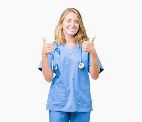 手で肯定的なジェスチャーを行う分離背景成功記号の上医療制服を着て美しい女医女性の親指を笑顔と幸せ 勝者ジェスチャー晴れやかな表情でカメラを見てください — ストック写真