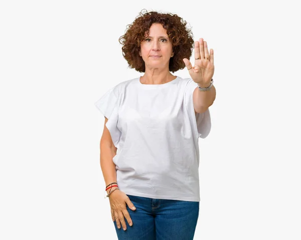 美丽的中间的高级妇女穿着白色的 T恤在孤立的背景做停止唱歌与手掌的手 脸上带有负面和严肃手势的警告表情 — 图库照片