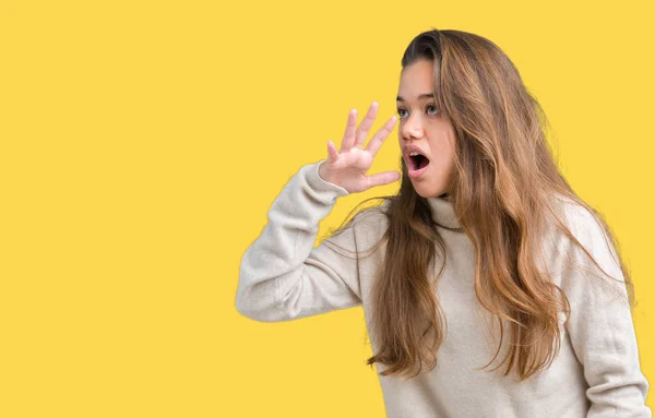 孤立した背景の上にタートルネックのセーターを着た若い美しいブルネットの女性は 口の上に手で横に大声で叫んで叫ぶ コミュニケーションコンセプト — ストック写真