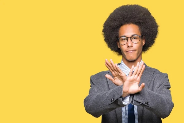 Young african american business man with afro hair wearing glasses Rejection expression crossing arms and palms doing negative sign, angry face