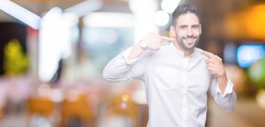 Genç iş adamı kendine güvenen gösterilen ve işaret parmakları diş ve ağız ile gülümseyen izole arka plan üzerinde. Sağlık kavramı.