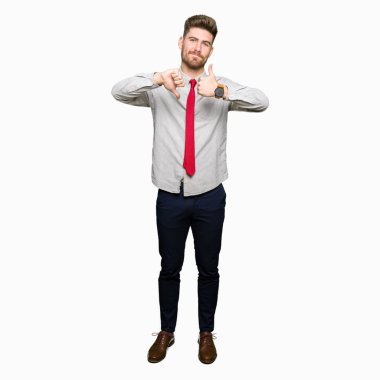 Genç yakışıklı iş adamı yapıyor başparmak yukarı ve aşağı, anlaşmazlık ve anlaşma ifade. Deli çatışma