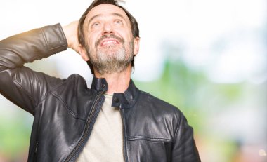 Siyah deri ceket giyen orta yaş yakışıklı adam el yukarı jest ile kendine güvenen dokunuşları gülümseyen, çekici poz