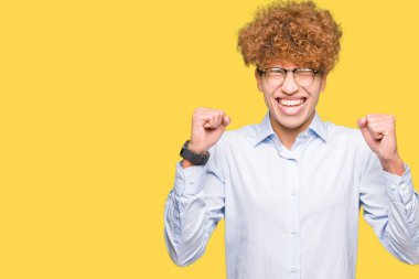 Genç yakışıklı iş adamı ile silah ile başarı için gözlük heyecanlı afro zafer kutluyor gülümseyen kaldırdı. Kazanan kavramı.