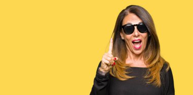 Güzel orta yaş kadın başarılı fikirle parmak işaret güneş gözlüğü takıyor. Çıktıktan ve mutlu. Bir numara.