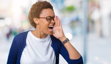 Bağırarak ve ağzı üzerinde el ile yan için çığlık izole arka plan üzerinde gözlük takan genç güzel Afrikalı-Amerikalı kadın. İletişim kavramı.