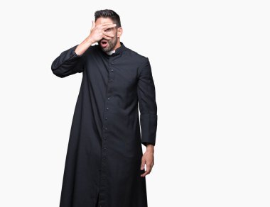 Genç Hıristiyan rahip yüz ve gözler el ile kapsayan şok bakmak izole arka plan üzerinde parmak utanç ifadesi ile üzerinden seyir.