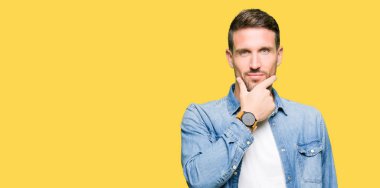 Emin çapraz kollar ve çeneme kaldırdı el ile gülümseme ile kamera seyir kot ceket giyen sakal ve mavi gözlü yakışıklı adam. Pozitif düşünce.