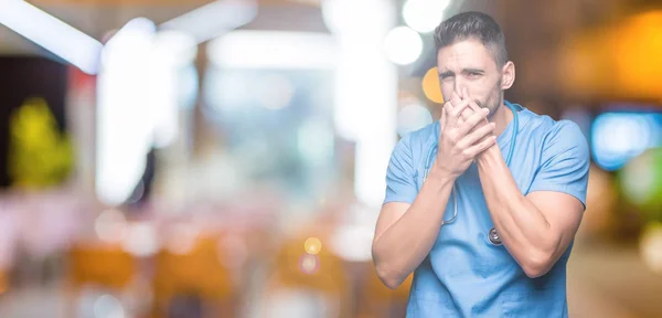 Joven Médico Cirujano Guapo Sobre Fondo Aislado Oliendo Algo Apestoso — Foto de Stock