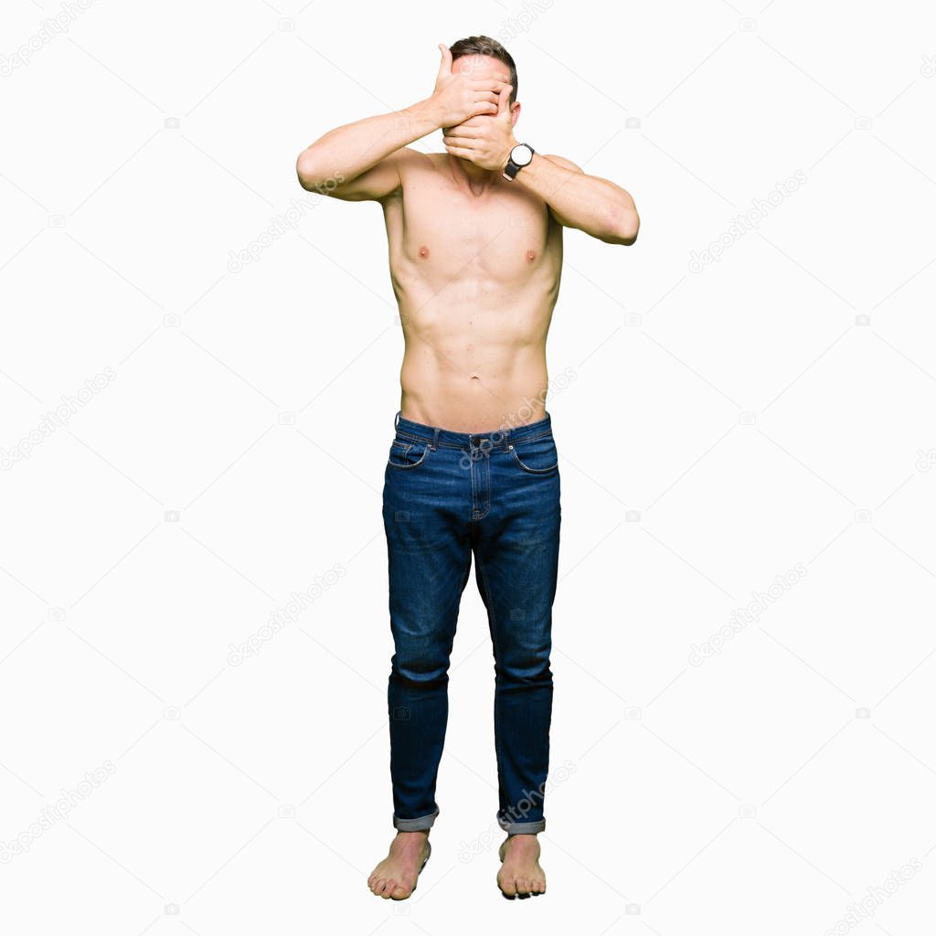 Handsome shirtless man showing nude chest Covering eyes and mouth with hands, surprised and shocked. Hiding emotion