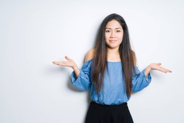 Güzel esmer kadın yüzünden izole arka plan clueless ve şaşkın bir ifadeyle kollar ve eller kaldırdı. Şüphe kavramı.