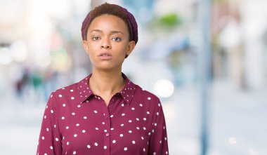 Üzerinde başörtüsü giyen güzel genç Afro-Amerikan kadın arka plan gevşek yüzünde ciddi bir ifade ile izole. Basit ve doğal kameraya bakıyor.