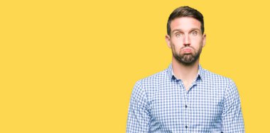 Komik surat ile yanakları şişirme mavi gözlü yakışıklı iş adamı. Ağız ile hava, deli ifade şişirilmiş.