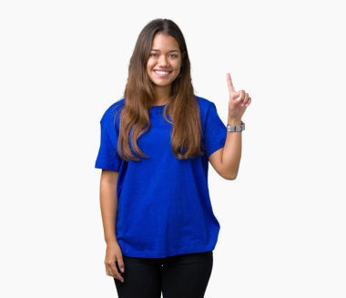 Ve kendinden emin ve mutlu gülümseyerek süre parmak numaralı yukarıyı gösteren izole arka plan üzerinde mavi t-shirt giyen genç güzel esmer kadın.