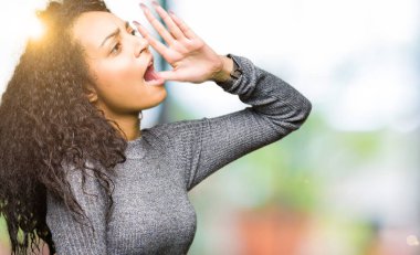 Genç güzel kız bağırarak ve ağzı üzerinde el ile yan için çığlık kıvırcık saçlı. İletişim kavramı.