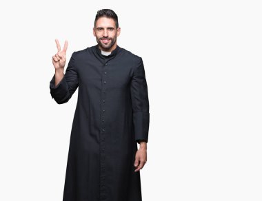 Genç Hıristiyan rahip gösterilen ve parmakları ile işaret izole arka plan üzerinde ikincisi ise kendinden emin ve mutlu gülümseyerek.