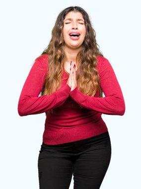 Yalvarıyor ve umut ifade yüzünde çok duygusal ve endişe ile birlikte elleriyle dua kırmızı kazak giyen genç güzel kadın. Bağışlanmak. Din kavramı.