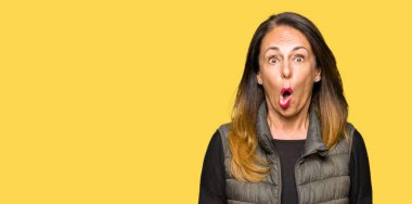 Güzel orta yaş kadın giyiyor kış yelek şüpheci ve alaycı, şok karşısında açık ağız ile şaşırttı