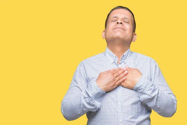 Middle age arab business man over isolated background smiling with hands on chest with closed eyes and grateful gesture on face. Health concept.