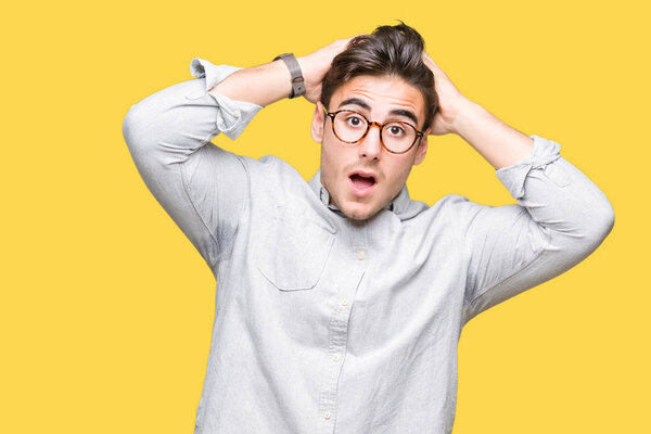 Young handsome man wearing glasses over isolated background Crazy and scared with hands on head, afraid and surprised of shock with open mouth