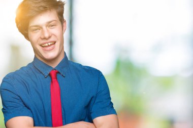 İzole arka plan üzerinde kırmızı kravat giyen genç yakışıklı iş adamı kamera bakarak çapraz silah ile gülümseyen yüz. Pozitif kişi.