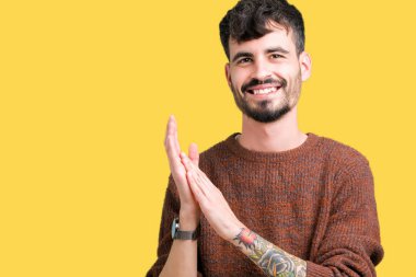 Genç yakışıklı adam giyen kış kazak izole üzerinde arka plan Clapping ve mutlu ve neşeli, gururlu gülümseyen birlikte eller alkış