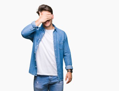 Genç yakışıklı adam gülümsüyor ve gözleri için sürpriz kapsayan yüz el ile gülüyor izole arka plan üzerinde güneş gözlüğü takıyor. Kör kavramı.