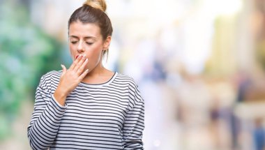 Genç güzel kadın rahat çizgili süveter izole arka plan üzerinde esneme yorgun kapsayan ağız el ile sıkılmış. Restless ve uyku hali.