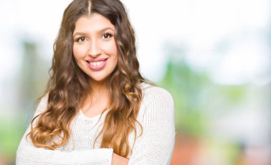 Beyaz kazak mutlu yüz ile gülümseyen giyen genç güzel kadın silah kameraya bakarak geçti. Olumlu bir kişi.