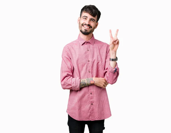 年轻的帅哥穿着粉红色的衬衫在孤立的背景微笑着 高兴的脸眨眼对着相机做胜利的标志 — 图库照片