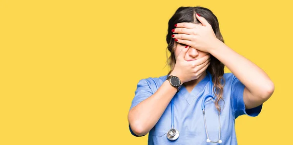 医療制服目を覆っていると 手で口を身に着けている若い大人医師女性は驚きし ショックを受けた 感情を隠す — ストック写真