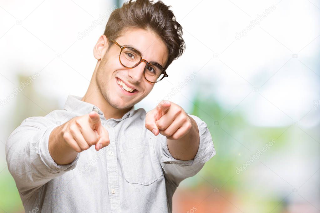 Young handsome man wearing glasses over isolated background Pointing to you and the camera with fingers, smiling positive and cheerful